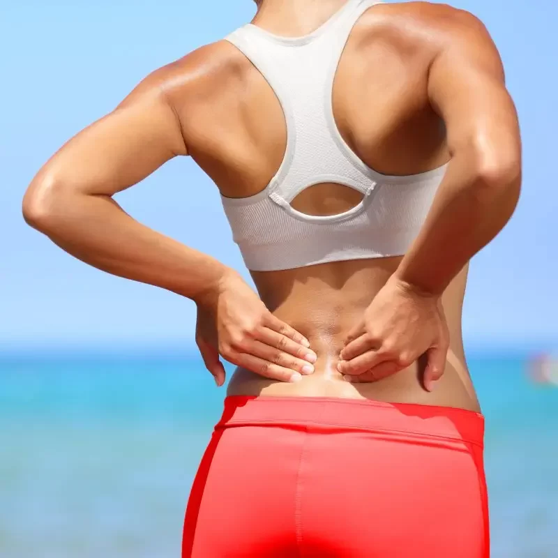 Woman holding her lower back in pain, indicating discomfort